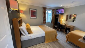 A hotel room with a bed, a desk, a chair, a television, and a wardrobe. - Shandon House (Richmond)
