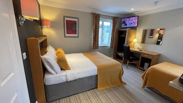 A hotel room with a bed, a desk, a chair, a television, and a wardrobe.