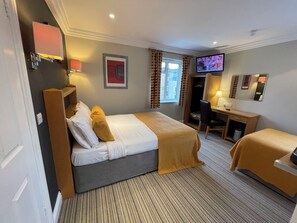 A hotel room with a bed, a desk, a chair, a television, and a wardrobe. - Shandon House (Richmond)