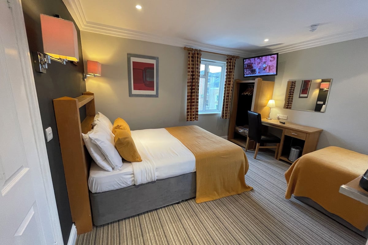 Ett hotellrum med en säng, ett skrivbord, en stol, en tv och en garderob.