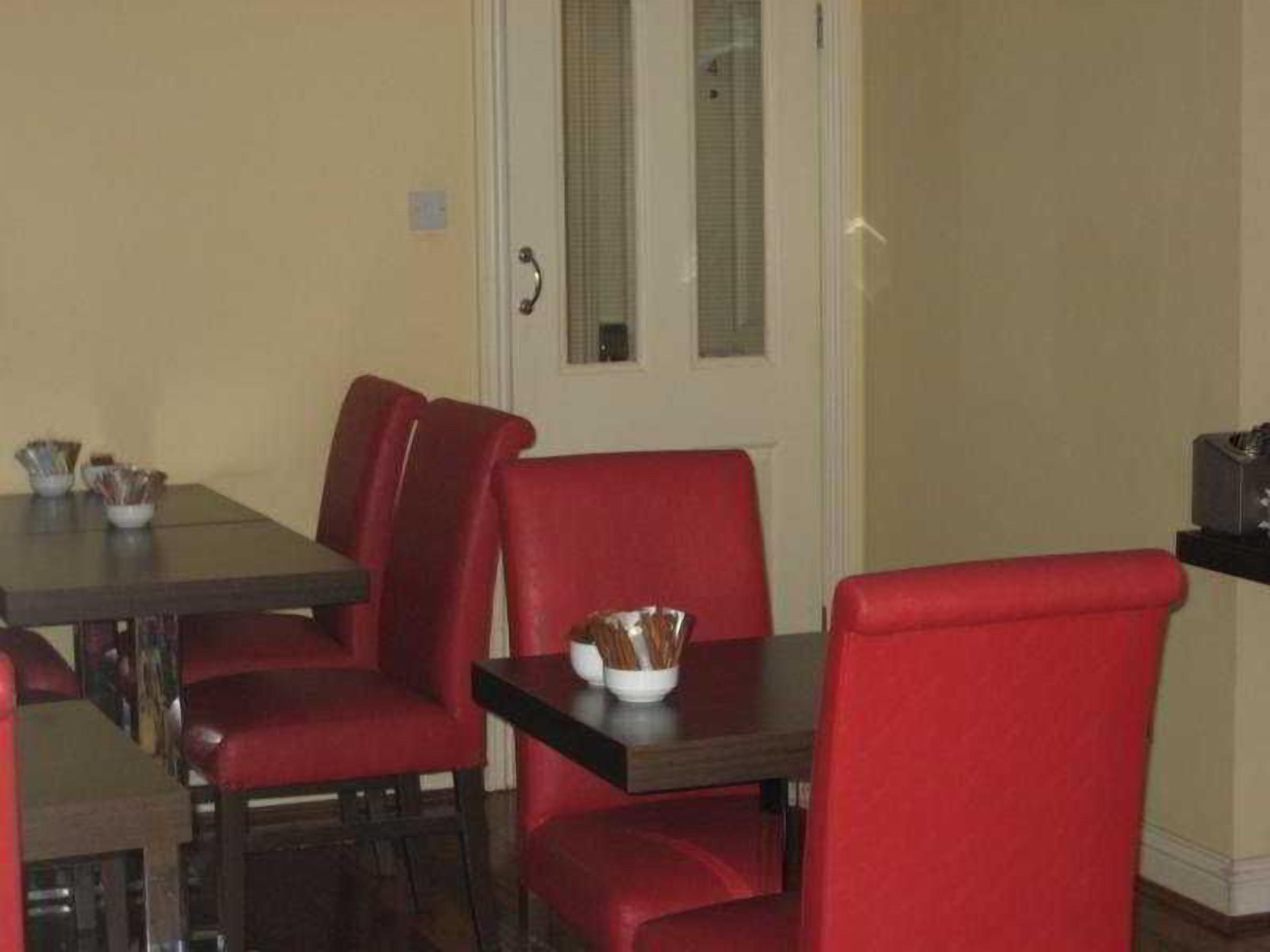 A dining area with a rectangular table and four red upholstered chairs.