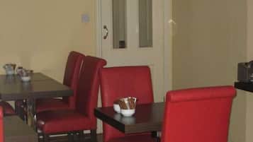 A dining area with a rectangular table and four red upholstered chairs.
