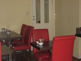 Un comedor con una mesa rectangular y cuatro sillas tapizadas en rojo.