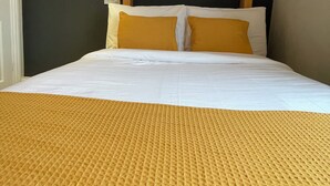 A hotel room with a bed, a headboard, a wall-mounted light, and a framed picture. - Shandon House (Richmond)