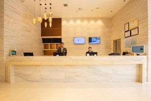 A hotel reception desk with two staff members, a computer, and a television screen. - City Comfort Inn Xiantao First Middle School (Xiantao)