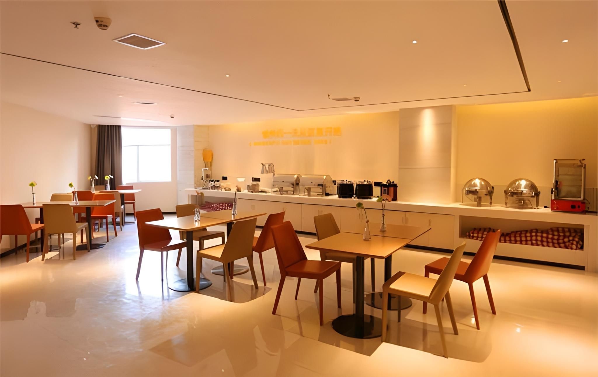 A modern dining area with tables and chairs, a kitchen counter with appliances, and a clean, minimalist design.