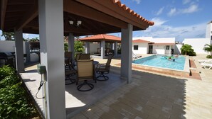 A covered outdoor area with a pool, seating, and a view of the surrounding buildings.