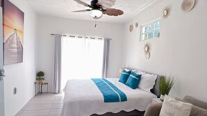 A bedroom with a bed, a ceiling fan, a window, and a plant. - Luxe Villa With Amazing Private Pool For 22 Guest (Manatí)