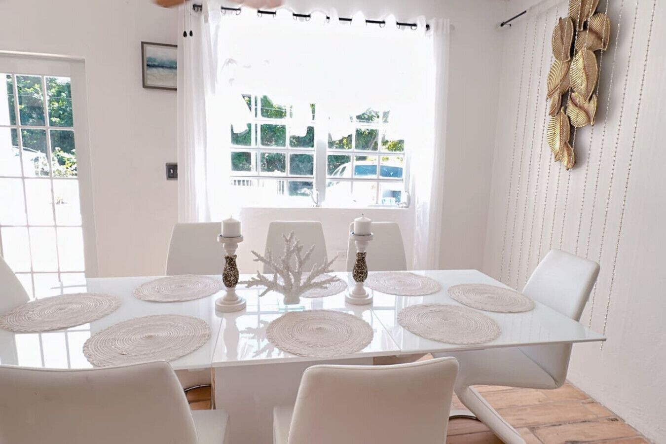 Une table à manger avec des sets de table blancs, des bougies et un centre de table décoratif.