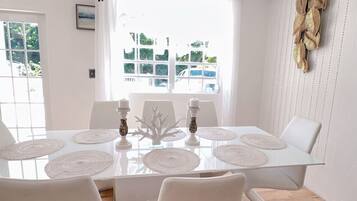 Une table à manger avec des sets de table blancs, des bougies et un centre de table décoratif.
