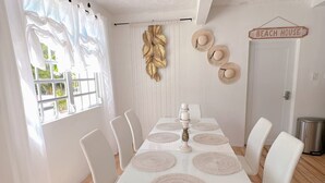 A dining area with a white table, white chairs, and a decorative wall piece. - Luxe Villa With Amazing Private Pool For 22 Guest (Manatí)