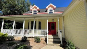 A yellow house with a red door, a covered porch, and a stone foundation. - Secluded retreat Heated pool 13 acres pool table playground (Union Pier)
