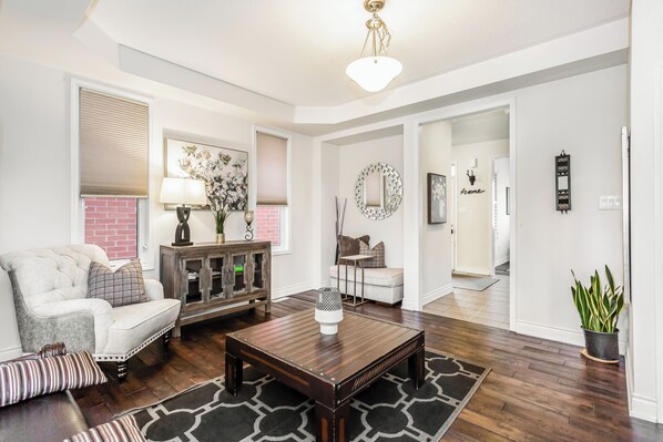 Un salon avec un canapé blanc, une table basse en bois foncé et un tapis à motifs.