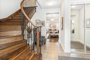 Un escalier en bois, doté d’une rampe en métal, mène à un espace de vie comprenant un canapé et une table basse.
