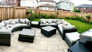An outdoor patio with a sectional sofa, two square ottomans, and a grill. - Milton Home away from home (Milton)