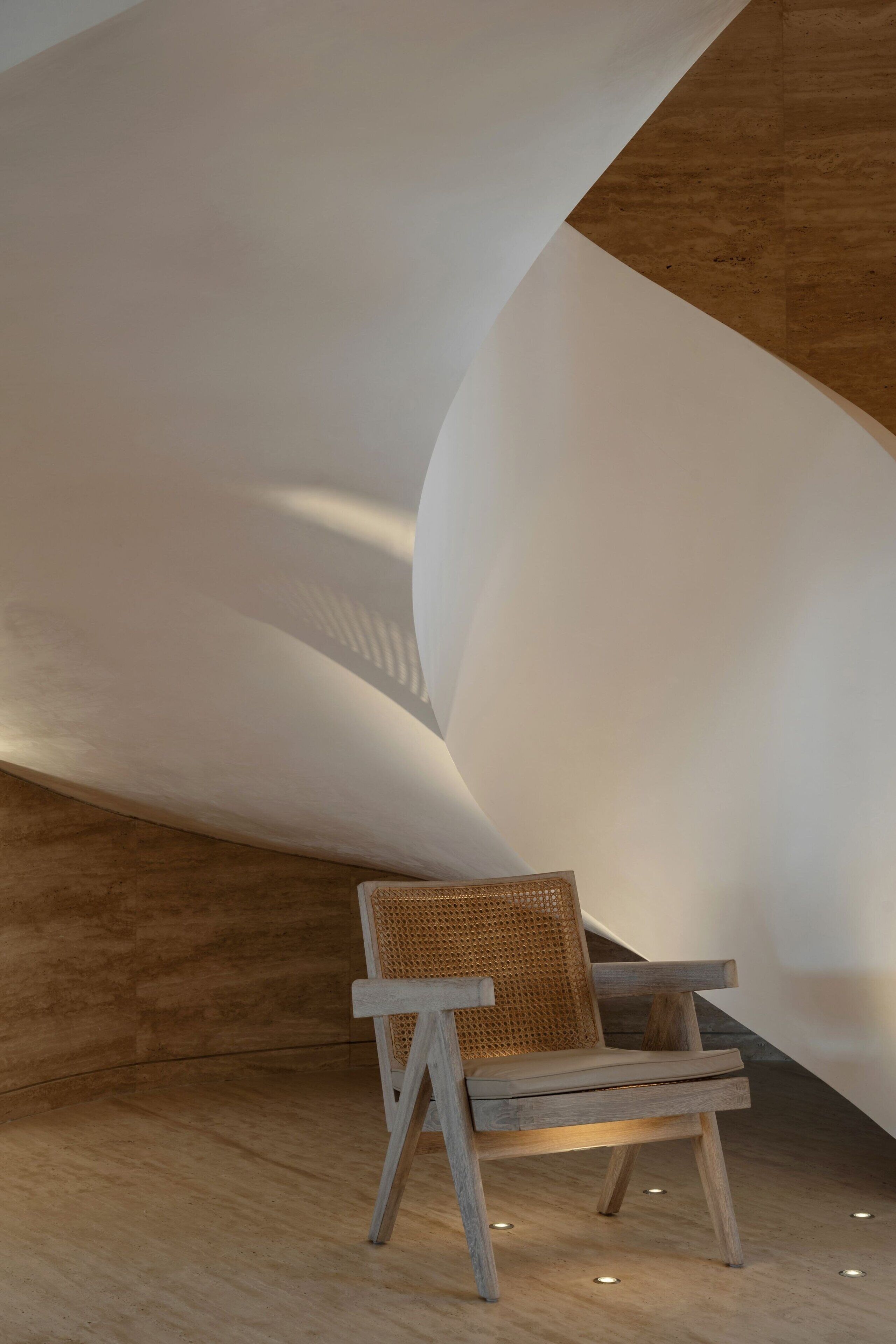 Ein modernes Interieur mit einem Holzstuhl und einem einzigartigen, geschwungenen Deckenbau.