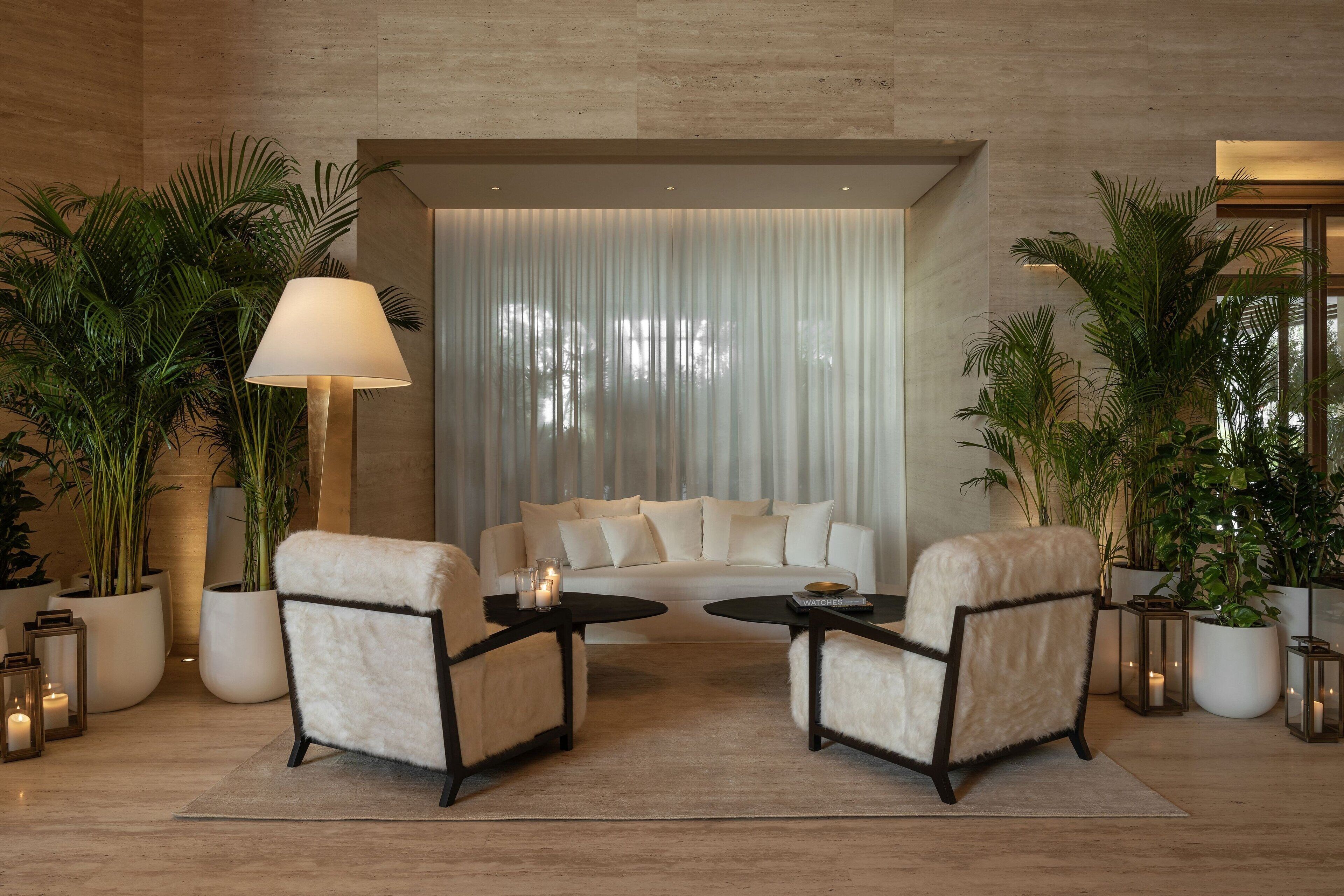 A modern living room with a sofa, two armchairs, a coffee table, and potted plants.