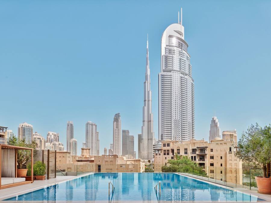 Una piscina sul tetto con lo skyline della città sullo sfondo, incluso un grattacielo di rilievo.
