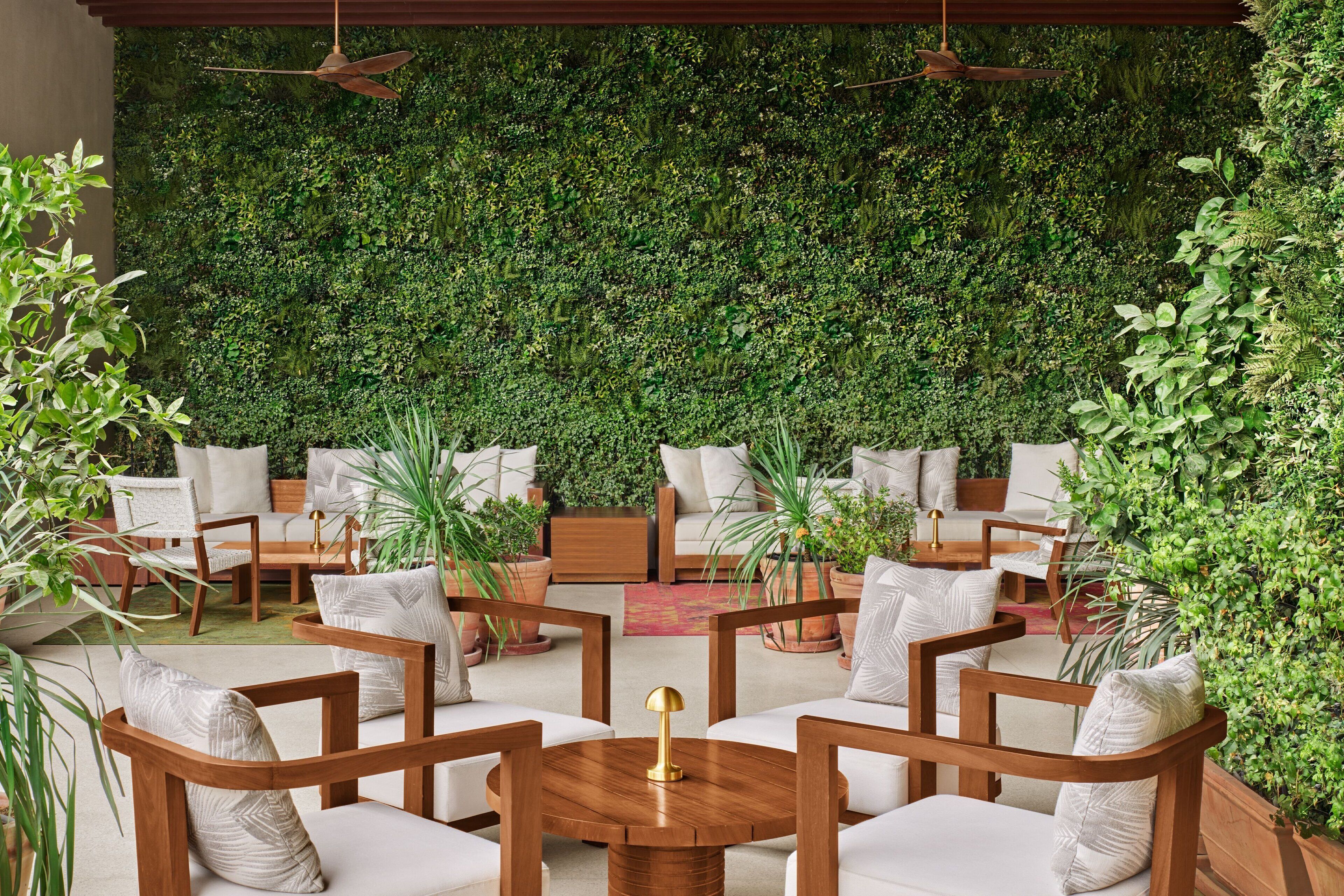 A cozy outdoor seating area with wooden furniture and a lush green wall backdrop.