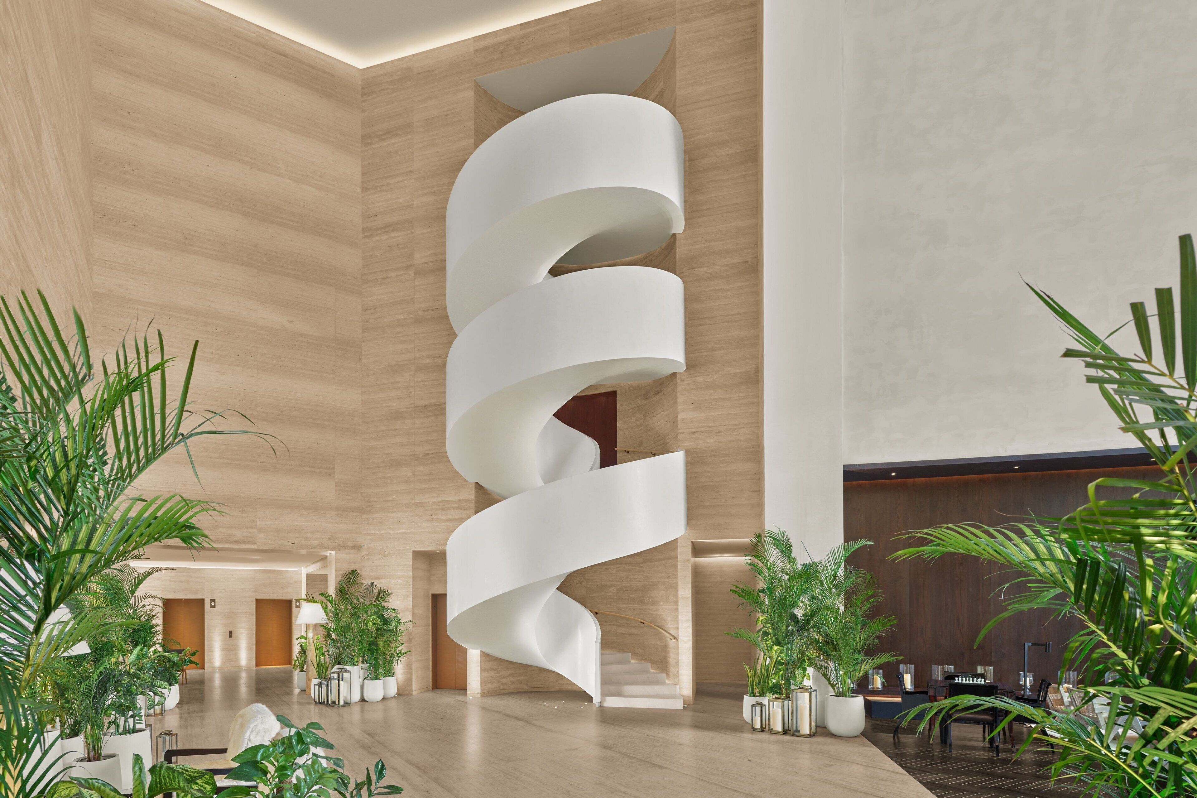 A modern lobby with a spiral staircase, wooden walls, and potted plants.