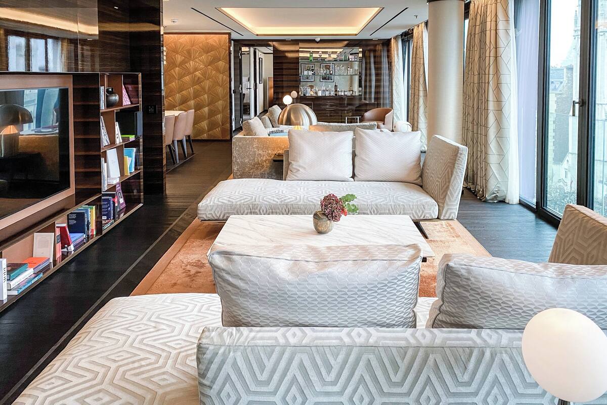 A modern hotel lobby with a large seating area, a bar, and a television.