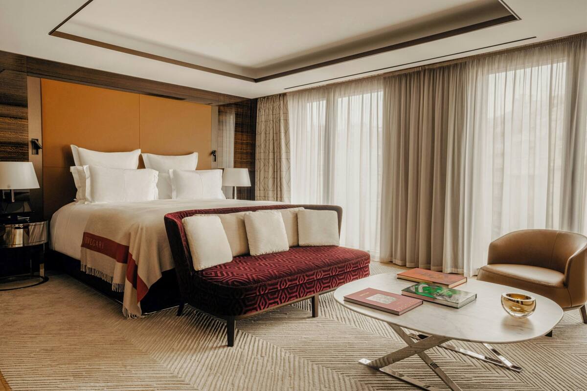 A hotel room with a large bed, a sofa, a coffee table, and a chair.