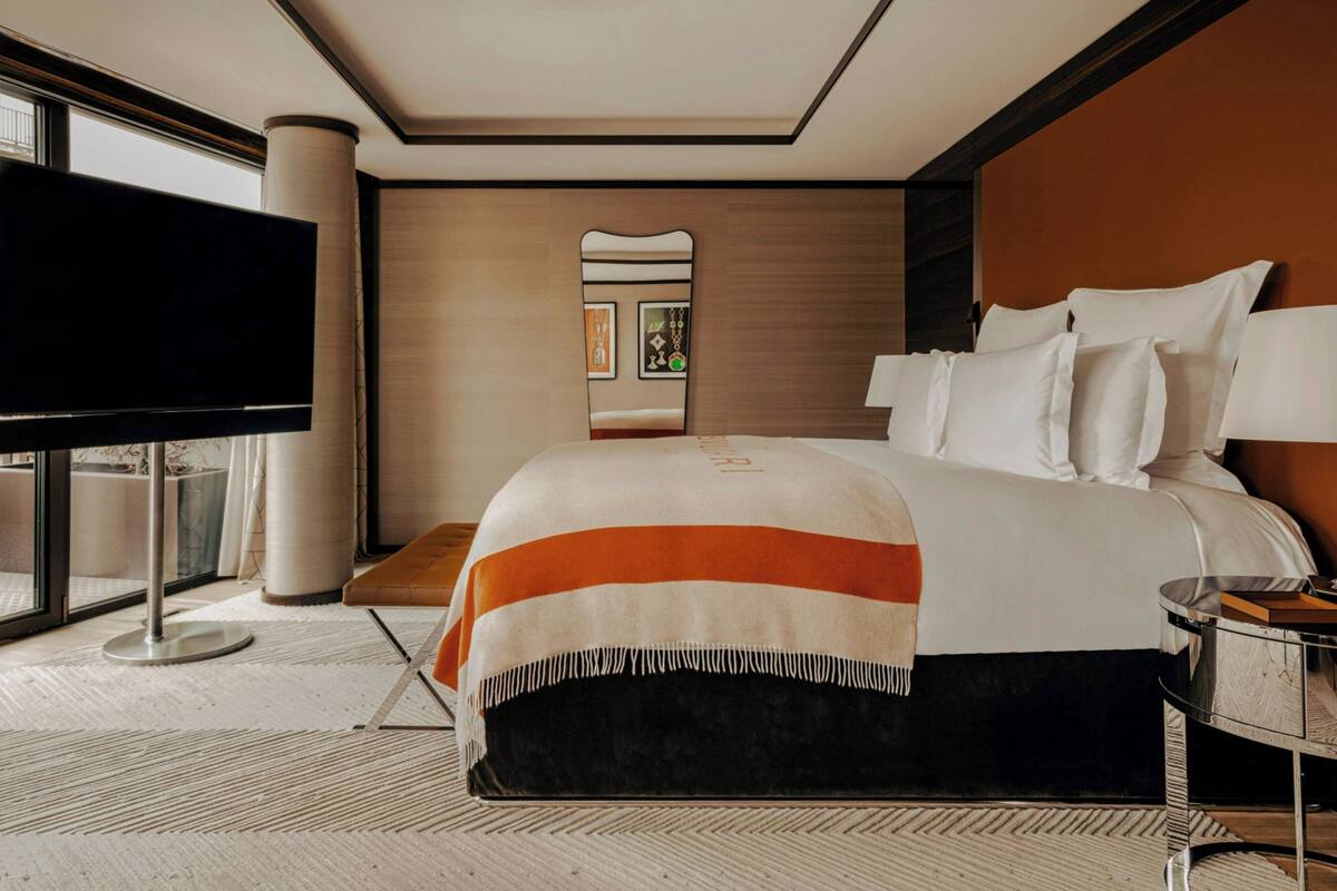 A modern hotel room with a large bed, a flat-screen TV, a bedside table, and a large window.