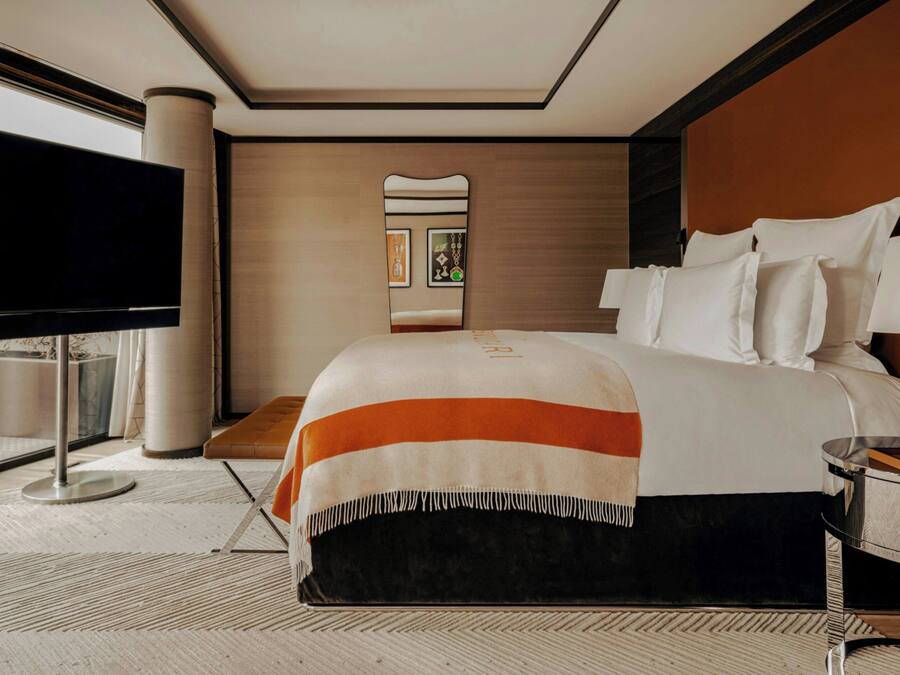 Ein modernes Hotelzimmer mit einem großen Bett, einem Flachbildfernseher, einem Nachttisch und einem großen Fenster.