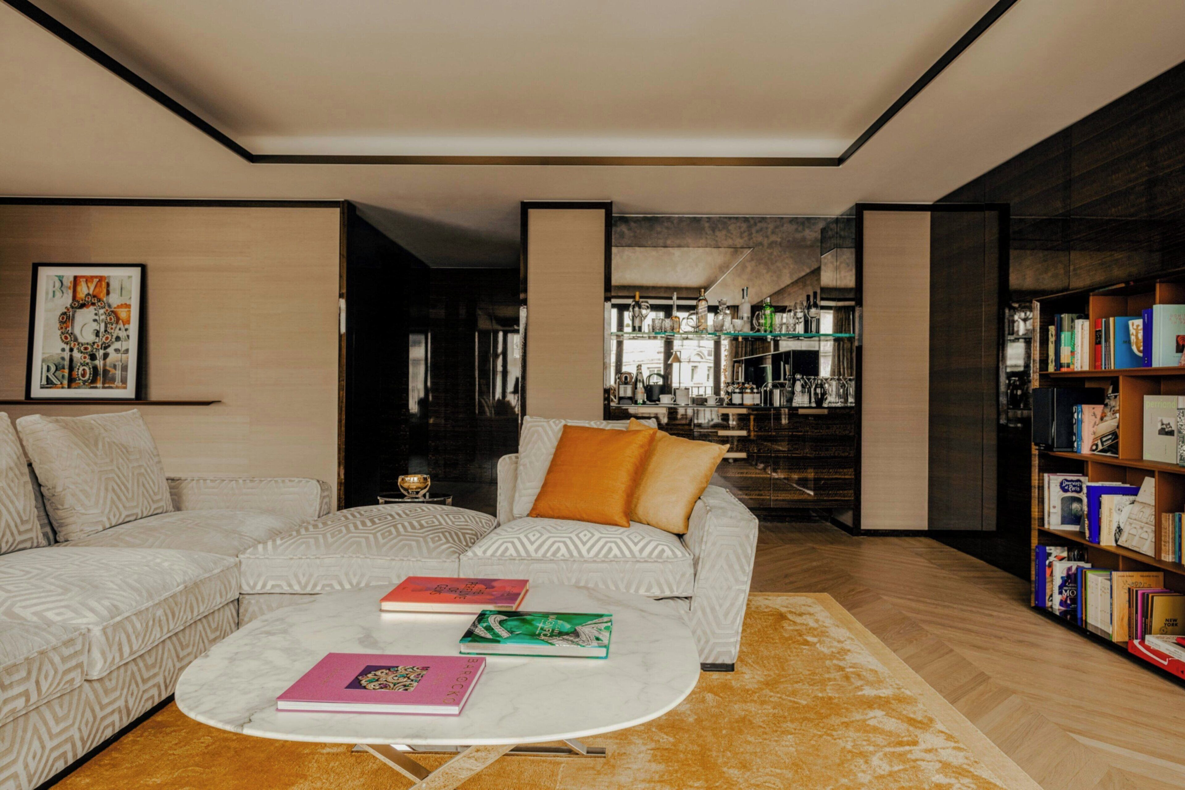 A modern living room with a sectional sofa, a coffee table with books, and a bookshelf.