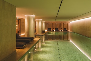 A modern indoor pool area with seating and large cylindrical light fixtures.