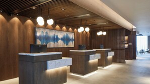 Un área de recepción con paneles de madera, mostradores de mármol y un cuadro abstracto de gran tamaño.