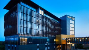 Un hotel moderno con fachada de vidrio, un patio interior y un letrero que indica que es un Courtyard by Marriott.