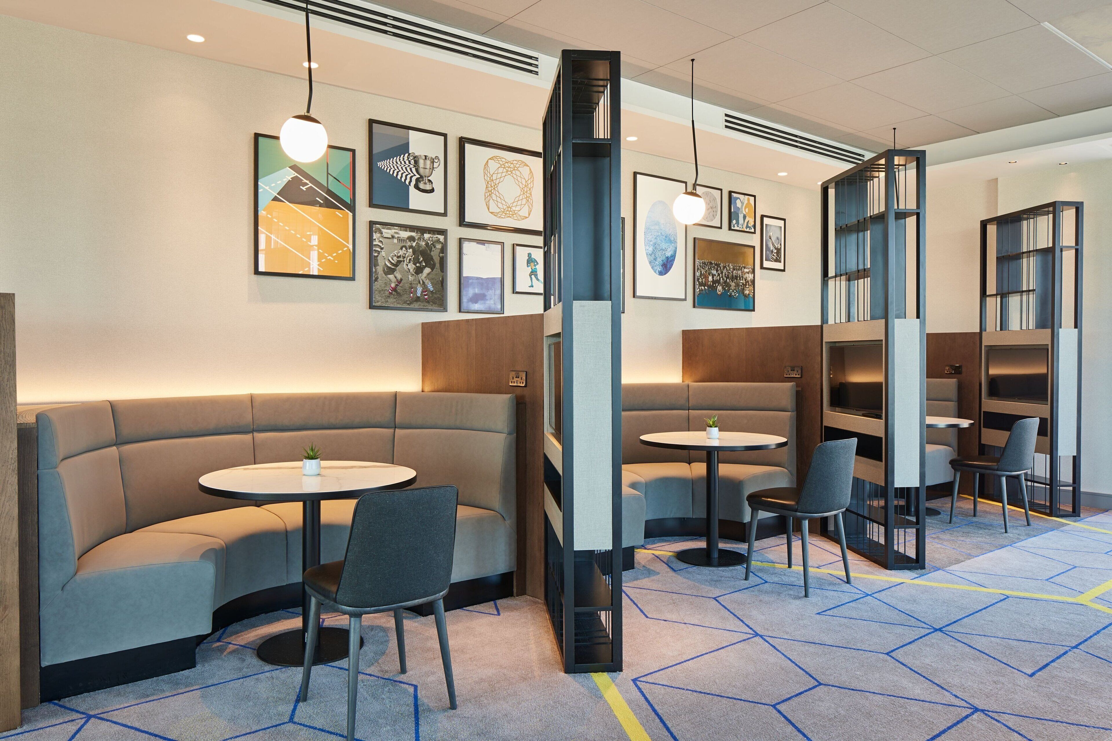 Ett modernt loungeområde med bekväma sittplatser, runda bord och en matta med geometriskt mönster.