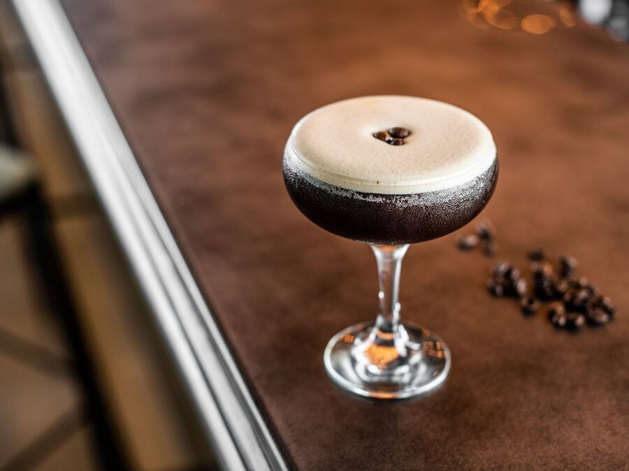 A cocktail in a martini glass on a bar counter.