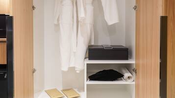 A walk-in closet with white robes hanging on a rack, a black suitcase, and a pair of shoes on the lower shelf.