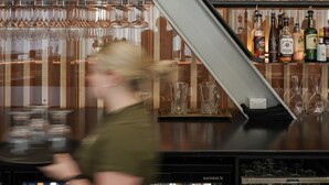 A bar area with a sign reading "Two Doors Down" and a variety of liquor bottles and glasses. - The Langlands Hotel (Invercargill)
