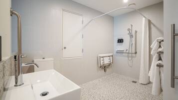 A modern bathroom with a white sink, a shower with a handheld showerhead, and a towel rack.
