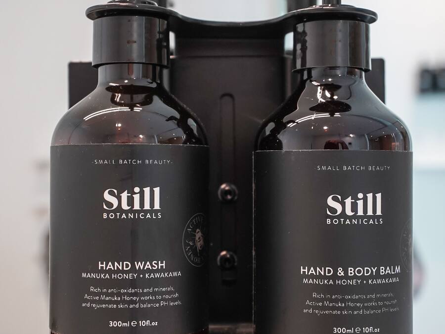 Two Still Botanicals hand wash and body balm bottles on a countertop.