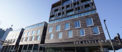 A multi-story hotel with a modern design, featuring large windows and a prominent signage for "The Langlands".