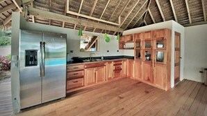 Una cocina amplia con armarios de madera, un refrigerador de acero inoxidable y techo de madera.