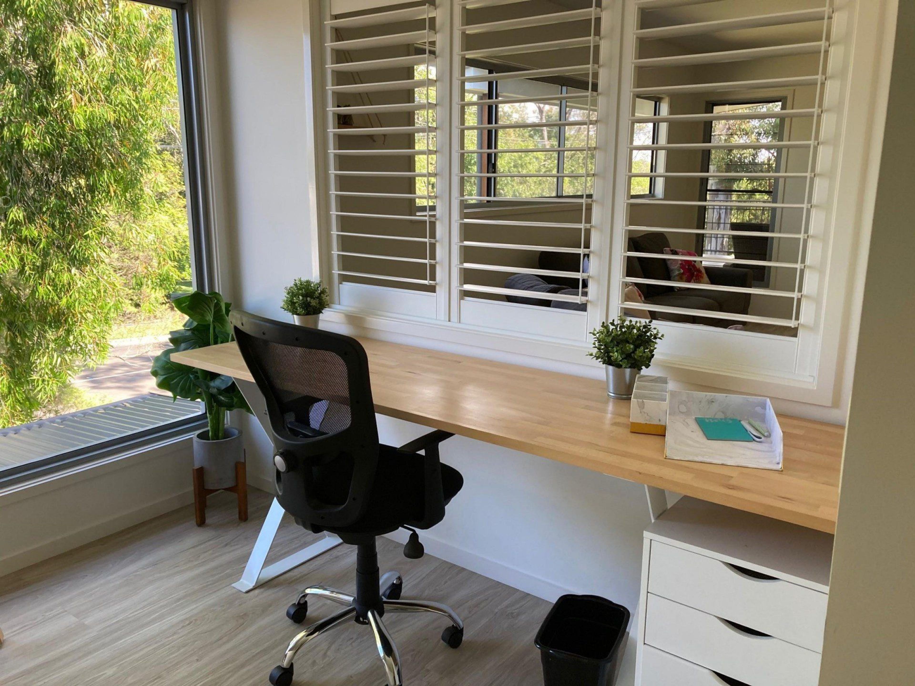 A modern office space with a desk, chair, and window blinds.