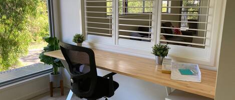 Un espace de bureau moderne comprenant un bureau, une chaise et des stores aux fenêtres.