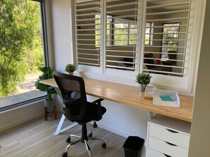 A modern office space with a desk, chair, and window blinds.