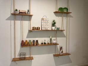 Un mur orné de trois étagères en bois, chacune supportant divers objets décoratifs et plantes.