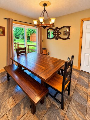 A dining area with a wooden table and benches, a chandelier, and a view of the outdoors. - Cozy Cabin Retreat Sleeps 12 w/ HotTub, Wi-Fi, FirePit minutes from Dollywood!! (Sevierville)