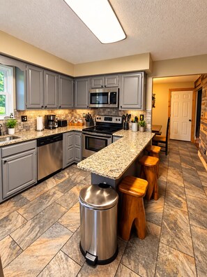 A modern kitchen with grey cabinets, stainless steel appliances, and a granite countertop. - Cozy Cabin Retreat Sleeps 12 w/ HotTub, Wi-Fi, FirePit minutes from Dollywood!! (Sevierville)