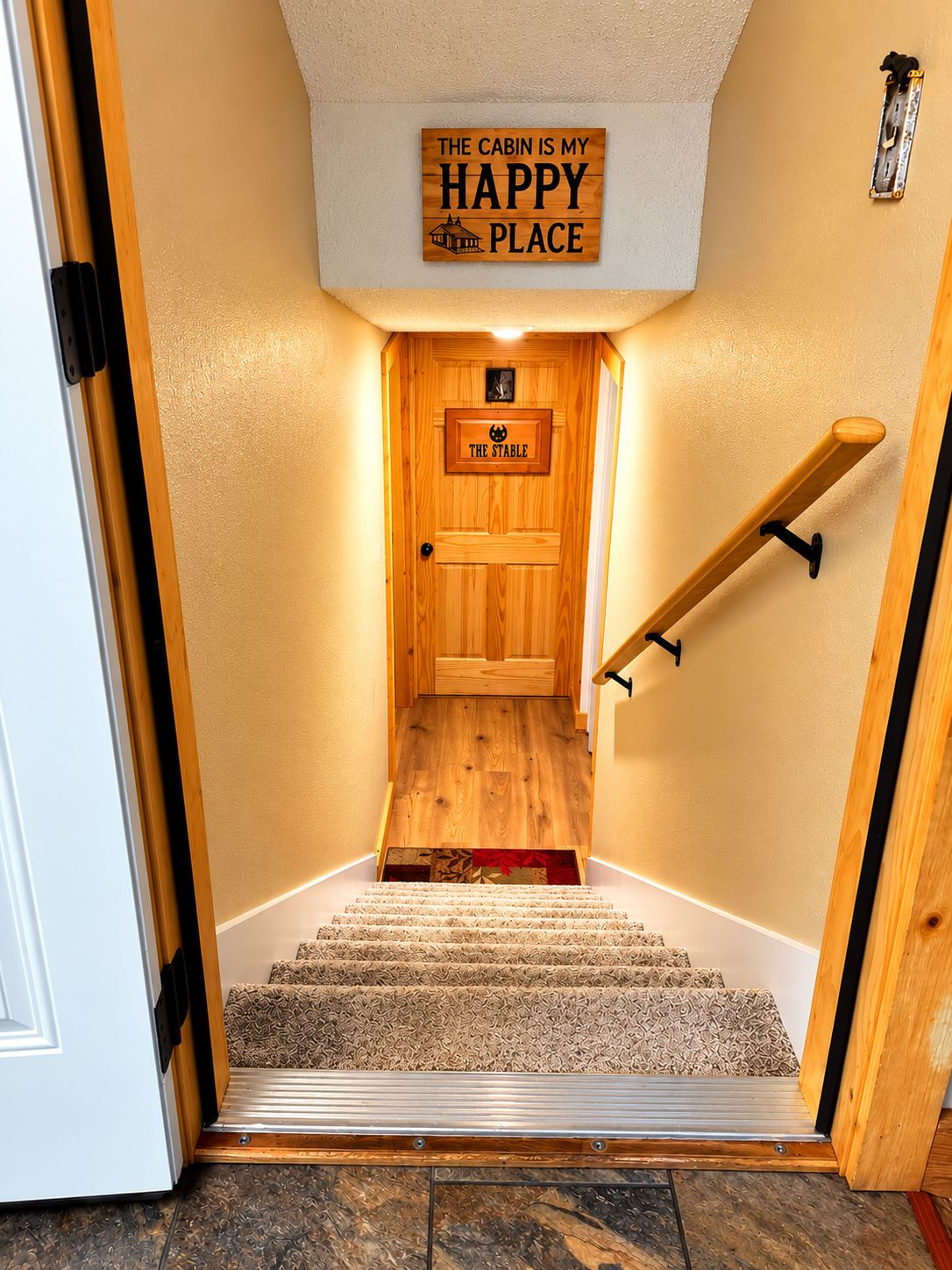 A wooden cabin interior with a staircase leading to a door labeled 'The Stable.'