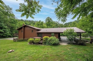 A rustic cabin with a wooden exterior, a covered porch, and a small garden area.