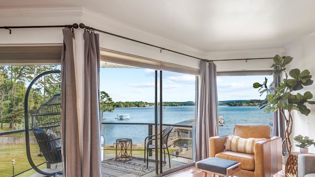 Ein geräumiges Zimmer mit einer großen Schiebetür, die auf einen Balkon mit Seeblick führt.