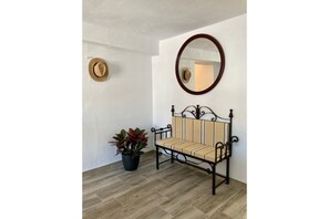 Simple, elegant room with a bench, mirror, and potted plant.